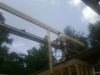 Carpenter setting a ridge beam over a new addition frame — Ice Dam Removal by Roofing Brothers in New Springfield