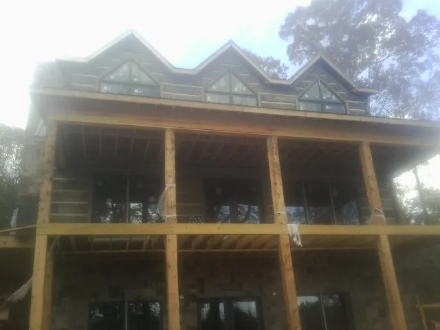 Dormers and porch framing on a large log home under construction — Roof Coating work by our crew in New Springfield
