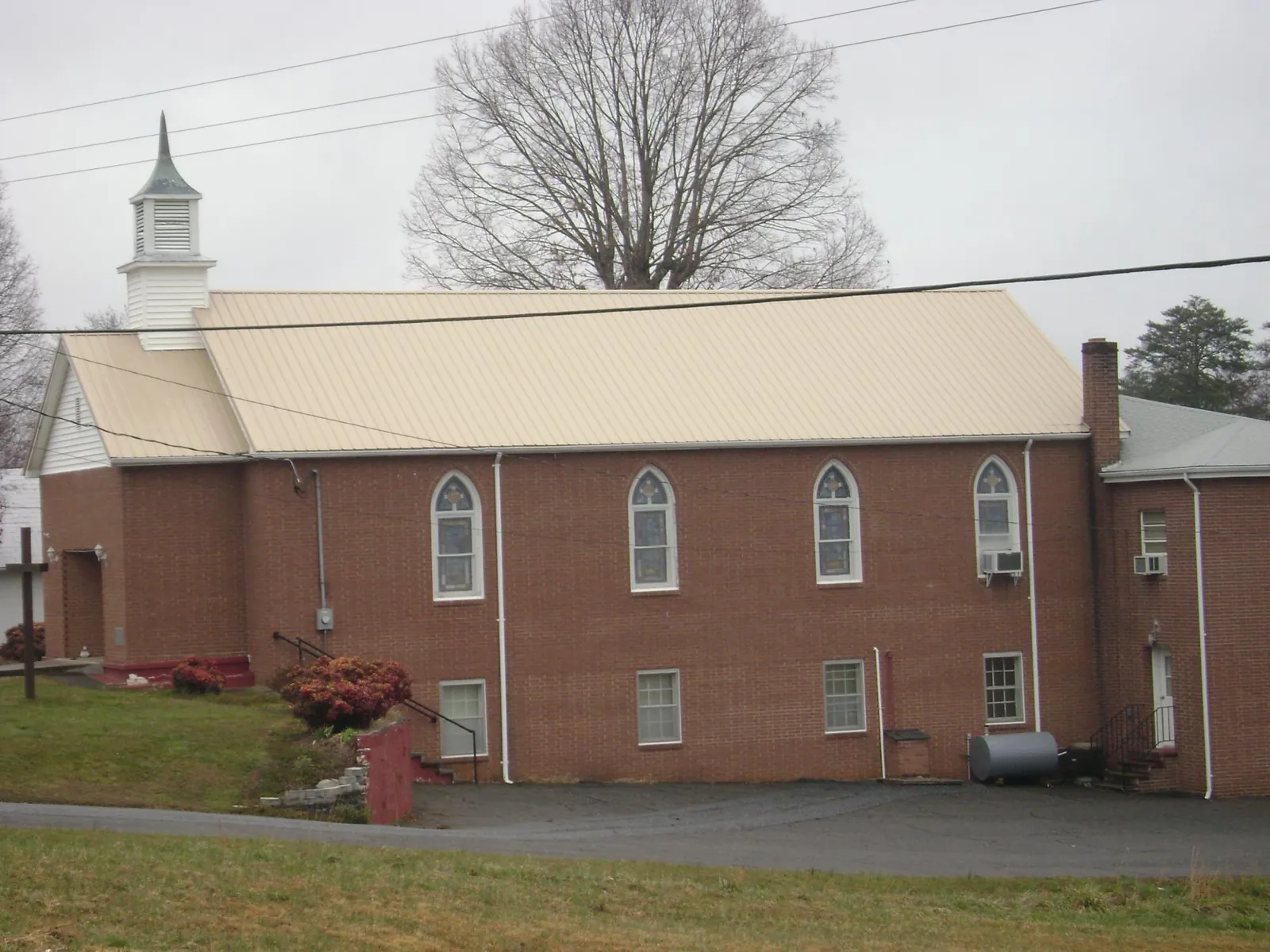 New tan metal roof on a brick church with a white steeple in New Springfield