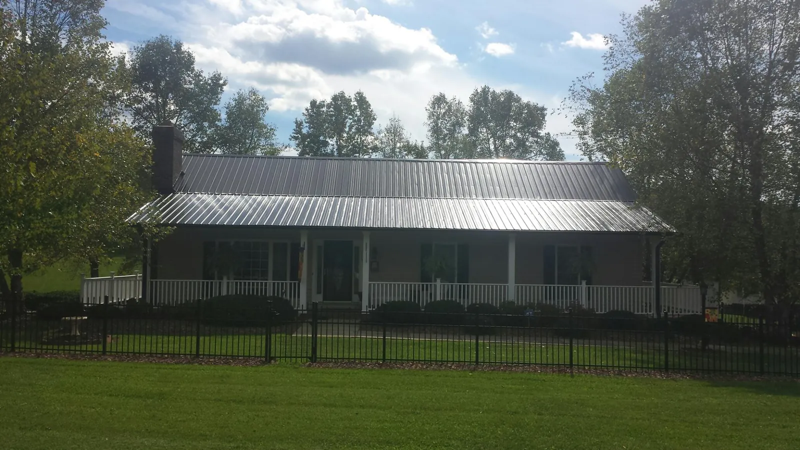 Gray metal roof on a brick ranch with a full width front porch — Gutter Guard Installation work by our crew in New Springfield