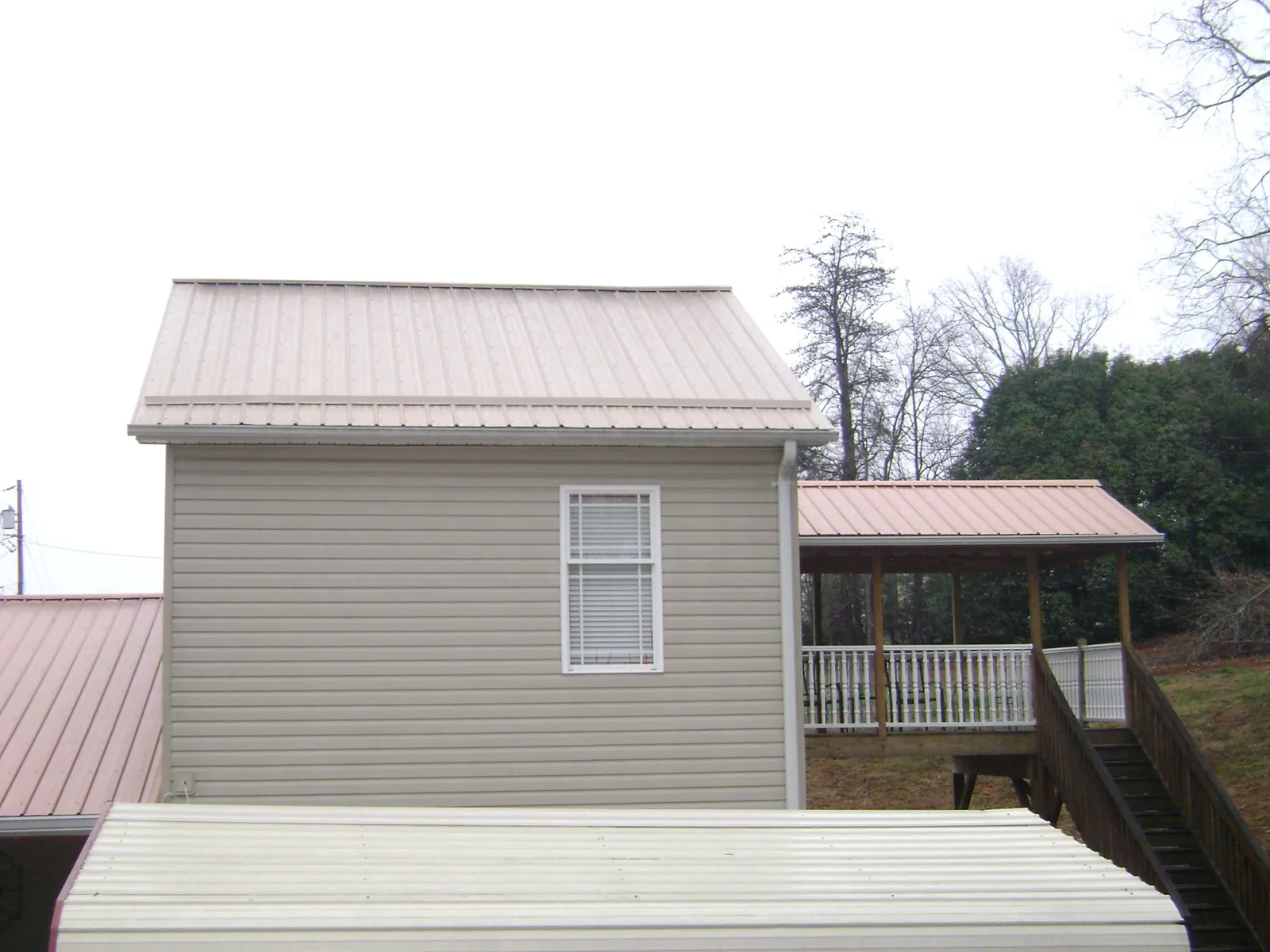 Tan metal roofs on a two story addition and attached porch, from a Roof Replacement job in New Springfield