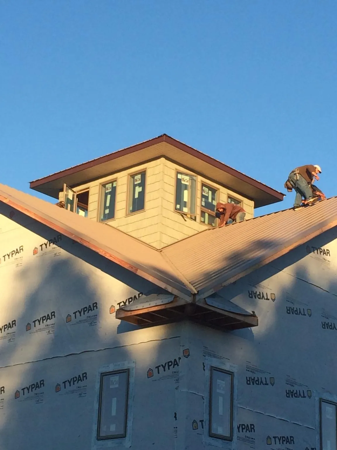 Roofers working around a rooftop cupola on a new metal roof at sunset — Roof Waterproofing in New Springfield by Roofing Brothers